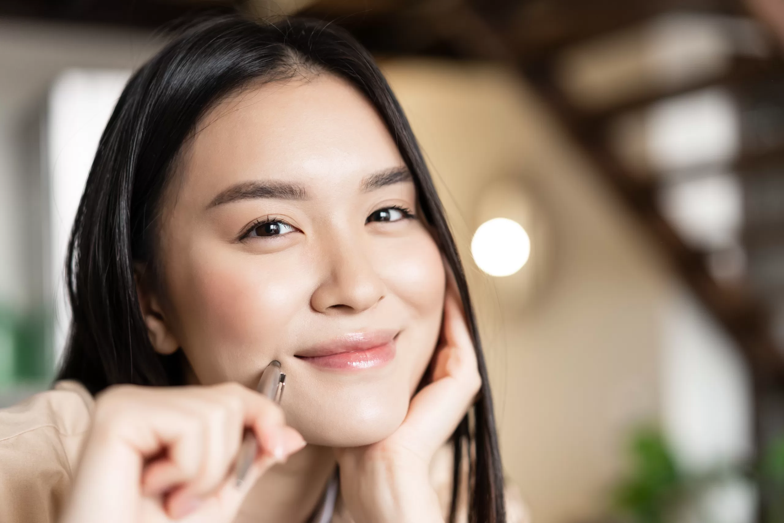 portrait smiling asian woman face looking happy holding pen grinning working doing homework scaled